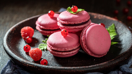 Homemade red currant macaroons on dark plate with fern