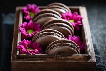 Homemade chocolate macaroons in wooden box with flowers