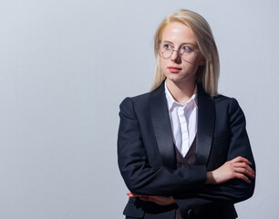 Beautiful blonde businesswoman in suit on gray background