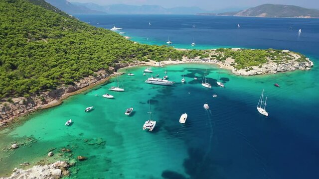 Aerial drone video of small tropical Caribbean island with beautiful turquoise and sapphire clear sea covered with pine trees