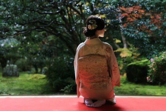 Japanese Woman In Kimono Sitting In Front Of A Japanese Garden