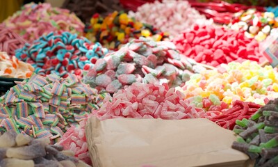 Close up of piles of colorful jelly candies in a market. Paper bags for buy and pack the sweets....