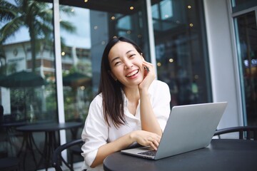 Smiling Asian woman with laptop.