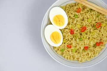 Bowl Of Instant Noodle With leek, Red Chilli and Bamboo Chopsticks On White Background