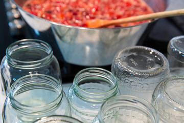 Empty jars for jam on the table. Cooking strawberry jam in a large bowl at home.