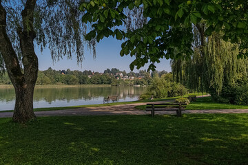 Idyllic atmosphere with a bench in front of a lanke in summer.