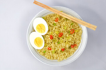 Bowl Of Instant Noodle With leek, Red Chilli and Bamboo Chopsticks On White Background