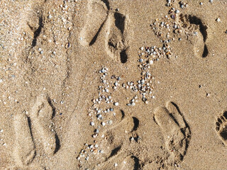 Many prints of male feet on the sea sand. Walk barefoot along the shore with footprints. Tourist rest.