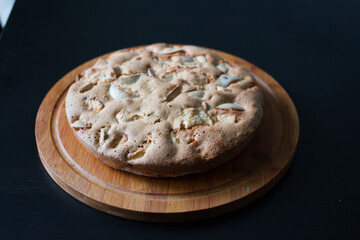 Homemade Apple pie lying on a round wooden Board.