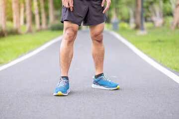 Young adult male in sport shoes ready to running in the park outdoor, runner man jogging and walking on the road at morning, leg muscles of Athlete. Exercise, wellness, healthy lifestyle and workout