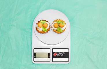 Two cakes in the form of baskets with mushrooms are on the kitchen scales.
