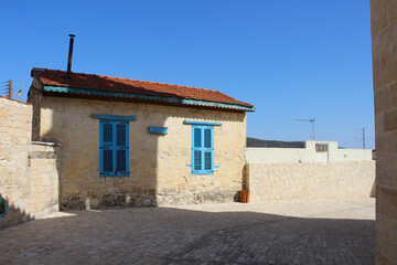 Stone house with blue Windows and tiled roof on the street of the Cyprus village . Cyprus.