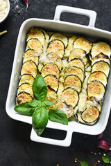 Zucchini casserole with cream, garlic and parmesan on a black background. View from above.