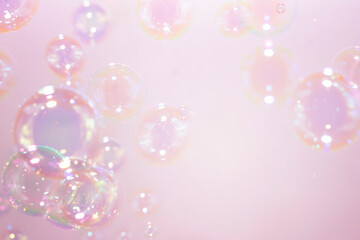 Beautiful rainbow soap bubbles float on pink background. Abstract bubble blur background.
