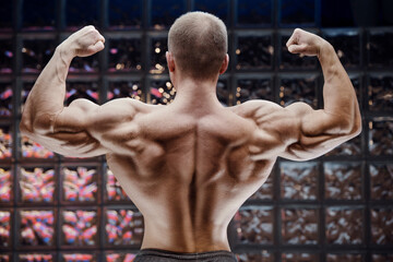 Fototapeta na wymiar Bodybuilder strong man pumping up biceps muscles.