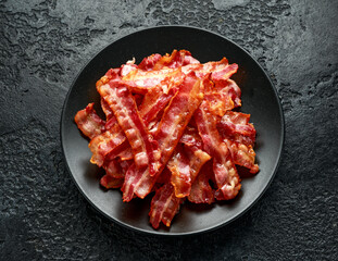 Fried crunchy Streaky Bacon pieces in a black plate