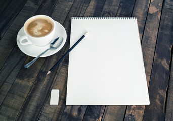 Blank sketchbook, coffee cup, pencil and eraser on vintage wooden background. Responsive design mockup.