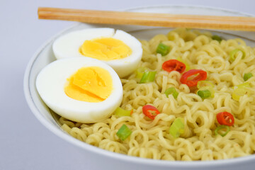 Bowl Of Instant Noodle With leek, Red Chilli and Bamboo Chopsticks On White Background