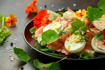 Smoked salmon and cucumber salad with nasturtium leaves and edible flowers. healthy food