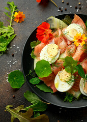 Smoked salmon and cucumber salad with nasturtium leaves and edible flowers. healthy food
