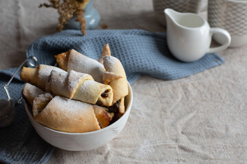 Homemade pastry. The rugelach with jam in a white bowl on a table. Traditional Jewish holiday cookie. Bagels. Croissants. Still life photography with cookies.