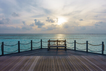 Fototapeta premium Wooden bench on jetty with sunrise in the morning
