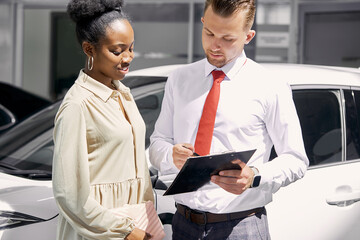 good-looking dark-skinned woman have conversation with salesman in dealership, professional sales...