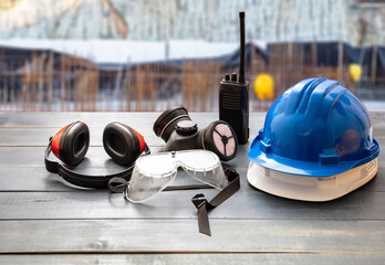 Work safety protection equipment. Industrial protective gear on wooden table, blur construction site background.