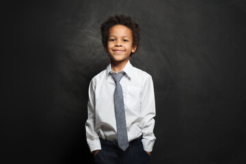 Black child boy in white shirt and tie on black background © millaf (Nemchinova)