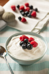 Bowl of Fresh Mixed Berries and Yogurt Served on a Light Blue and White Cloth