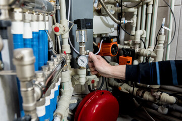 Heating engineer fixing modern heating system in boiler room. 