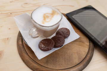 a cup of cappuccino, tree biscuits, and a mobile device