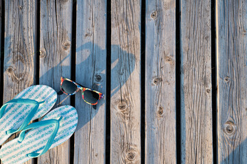 Blue Bright Slippers and Colourful Sunglasses on an Old Wooden Background