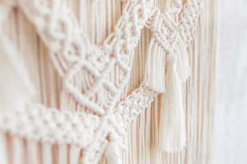 Fototapeta na wymiar Close-up of hand made macrame texture pattern. ECO friendly modern knitting DIY natural decoration concept in the interior. Flat lay. Handmade macrame 100% cotton. Details close up. Female hobby.