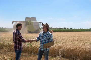Farmers shaking hands in field during harvest