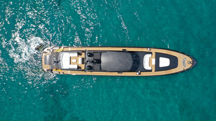 Aerial drone top view photo of large black yacht - boat with wooden deck anchored in tropical exotic paradise with turquoise open sea