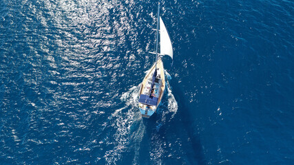 Obraz premium Aerial drone photo of sail boat cruising in the deep blue Aegean sea, Cyclades, Greece