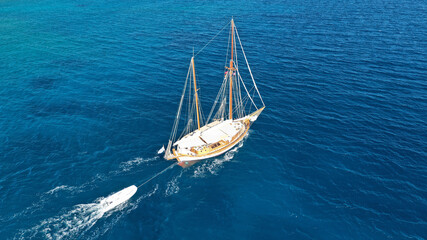 Aerial drone photo of beautiful wooden deck classic sailing yacht cruising in open ocean deep blue sea