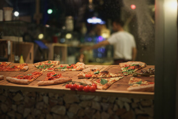 Naklejka na ściany i meble Small italian pizzeria with pieces of pizza in the window
