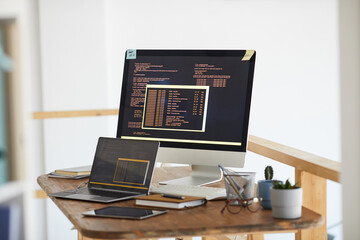 Background image of black and orange programming code on computer screen and digital devices in modern white office interior, copy space