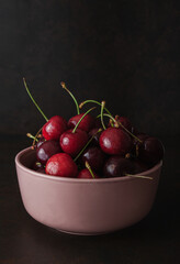 Cherry with leaf on plate and water drops on dark brown stone table. Ripe ripe cherries. Sweet red cherries. Top view. Rustic style. Fruit Background