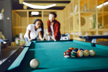 Black girl in a white t-shirt. Couple playing a billiard