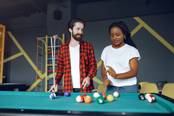 Fototapeta premium Black girl in a white t-shirt. Couple playing a billiard
