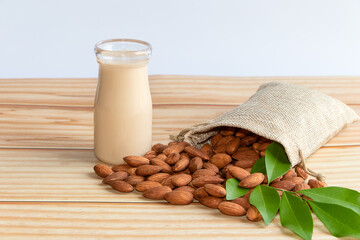 Almond milk in glass with almonds on wooden table