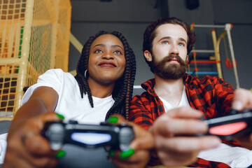 Fototapeta na wymiar Black girl in a white t-shirt. Couple playing a video games. People use a joystick