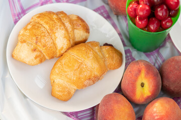 Picnic in the Park in summer on the grass. Peaches, croissants, berries on the tablecloth