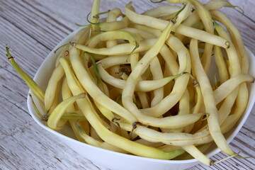Fresh string bean close up in white bowl on wooden table
