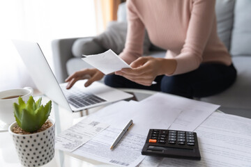Crop close up of economical woman work on laptop at home pay bills taxes on gadget online,...