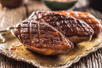 Crispy grilled duck breasts resting on a vintage plate