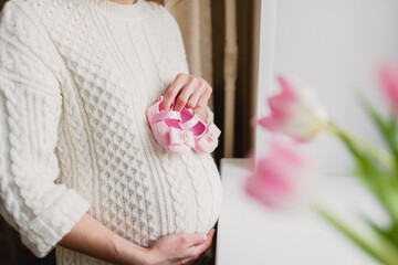 Pregnant woman holds baby shoes in her hands